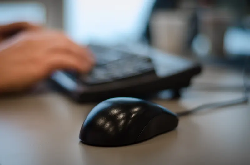 Businessperson reviewing a printed proposal document at a desk with a laptop