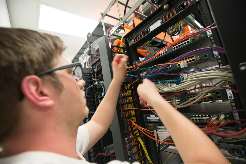 Fiber installation technician working at a spool of fiber-optic cable outside a commercial building