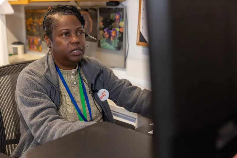 Office worker on a headset call with a customer record open on the monitor