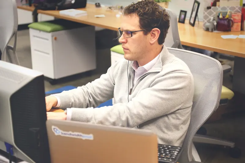 Business owner reviewing figures on a calculator and notepad at an office desk