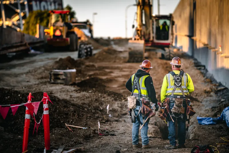 Construction crew reviewing plans on a tablet at an active building site
